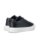 A pair of black leather low-top sneakers with chunky white platform soles, shown from a three-quarters angle on a white background.