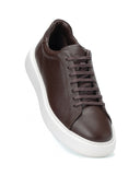 A dark brown leather low-top sneaker with matching brown laces and a thick white platform sole, shown from a three-quarters angle on a white background.