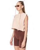 A woman modeling a sleeveless cropped top in light beige and matching brown fitted shorts against a plain white background.