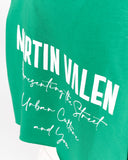 A close-up of a green t-shirt featuring a white graphic print that reads 'NRTIN VALEN' in bold block letters, followed by 'Presenting the Street Urban Culture and You' in a script font.