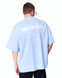 "Slogan" Men’s Oversized Printed Designer T-shirt in Blue worn with sunglasses and white low-top sneakers