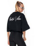 A woman shown from the back wearing a black cropped t-shirt with 'Martin Valen' written in white script across the back, paired with black leggings against a plain white background.