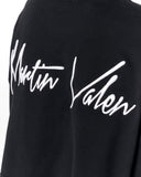 Close-up of a black sweatshirt featuring a large white embroidered script logo that reads 'Martin Valen' across the chest.