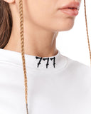 Close-up of a person wearing a white crewneck sweatshirt with a black '777' graphic printed on the inside of the collar.