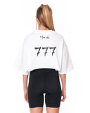A woman shown from the back wearing a white cropped T-shirt with black '777' graphics and 'Martin Valen' text, paired with black bike shorts, against a plain white background.