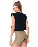 A woman shown from the back wearing a black sleeveless crop top and beige fitted shorts against a plain white studio background.