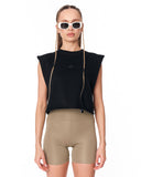 A model wearing a black sleeveless cropped top with a small embroidered crown logo on the chest, paired with beige fitted biker shorts and white-framed sunglasses, against a plain white background.