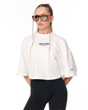 A woman modeling a white cropped t-shirt with 'Martin Valen' printed in black on the chest, paired with black leggings and sunglasses, against a plain white background.