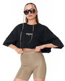 A model wearing a black cropped t-shirt with 'MARTIN VALEN' printed in white on the chest, paired with beige fitted biker shorts, against a plain white background.